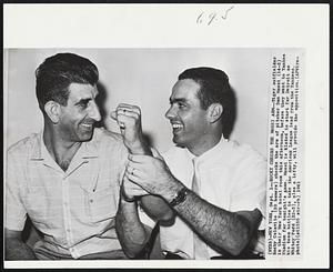 Rocky Checks the Mossi Arm -- Tiger outfielder Rocky Colavito (39 homers) checks the arm of pitcher Don Mossi (14-3) in their New York hotel room this afternoon, before they went to Yankee Stadium for tonight's game. Mossi is slated to start for Detroit as his team battles to take the American League lead from the Yankees. Whitey Ford (22-3), also a lefty, will provide the opposition.