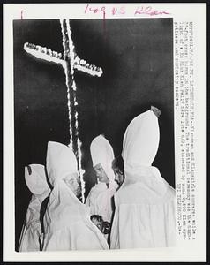 Klansmen and Klansgirls converse while a 35-foot cross burns in the background. The traditional ceremony was the highlight of a Ku Klux Klan rally here late 6/3, attended by some 2,500 Klan sympathizers and curiosity seekers.
