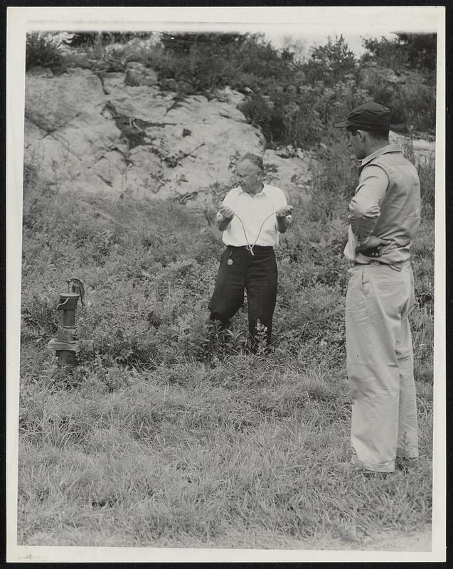 Locating a water vein near pump. Henry Gross- with water dowser. At right- Donald Bryant-foreman of Kenneth Roberts' farm.