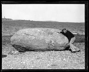 A man posing with a large boulder