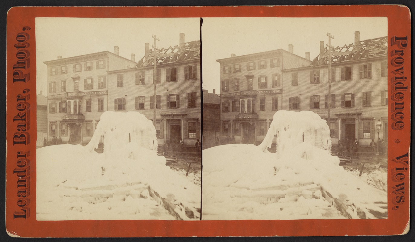 Snow and ice in foreground and storefronts and a burned out building in the background