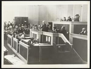 He Startled Geneva. British Foreign Secretary Samuel Hoare startled the League of Nations assembly here today when he asked that the league go the limit in applying sanctions for violations of the covenant. Sir Samuel may be identified in the center, standing behind the speaker's desk.