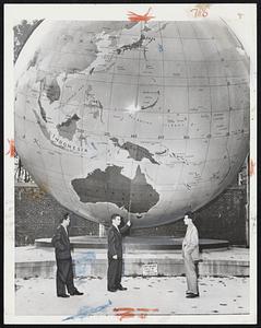 Dwarfed by huge globe on the campus of Babson Institute, Wellesley, Nobuo Yokata (left) and Sachito Sasaski (right). They listen as Leonard Smith gives quick geography lesson. Smith, president of the Student Council, pointed out sights durin a visit to school by two Japanese.
