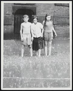 These Three Roxbury Children Don't Seem to Mind the Rain. Photo Was Made on Albany St. Weather - Storms - Rain - 8-5-52