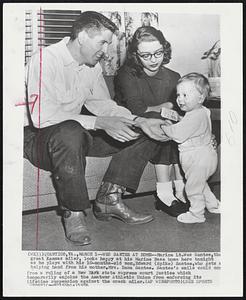 West Santee at Home--Marine Lt. Wes Santee, the great Kansas miler, looks happy at his Marine Base home here tonight as he plays with his 10-months-old son, Edward (Spike) Santee, who gets a helping hand from his mother, Mrs. Dana Santee. Santee's smile could come from a ruling of a New York state supreme court justice which temporarily enjoins the Amateur Athletic Union from enforcing its lifetime suspension against the crack miler.