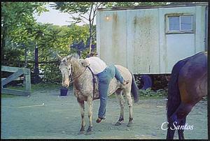 Cheryl Santos hopping on her horse Trinity in front of Charlie McQuiggan's trailer