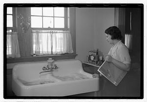 A woman looking at a sink full of laundry