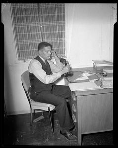 Man seated desk on telephone while smoking