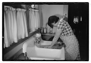 A woman doing laundry at a sink with a washboard