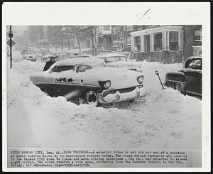 Kansas City -- Snow Troubles -- A motorist tries to get his car out of a snowbank as other traffic eases by on snow-slick streets today. The storm forced virtually all schools in the Kansas City area to close and made driving hazardous. The fall was expected to exceed eight inches. The storm covered a wide area, extending from the Eastern Rockies to the Ohio Valley.