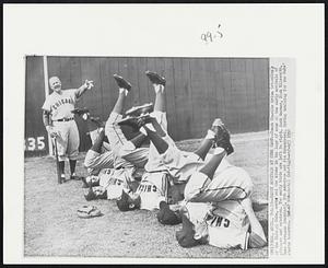 Mesa, Ariz. – Early Arrivals At Cubs Camp – Coach Charlie Grimm (standing), of the Chicago Cubs, works out the kinks in the legs of some of the early arrivals of pitchers and catchers. The early birds are left to right, Jack Warner, Dick Ellsworth, Cuno Barragan (catcher), Bob Anderson and Jim Schandevel. Spring training for the Cubs’ start tomorrow.