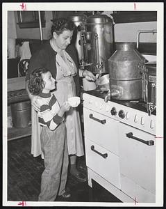 For Hungry Infants who were evacuated to our Lady of Loudres Church in Revere during the hurricane, Mrs. Anne Bernstein and her daughter, Eileen, 7, heat some milk. They were brought to a Red Cross center at the church with scores of other evacuees.