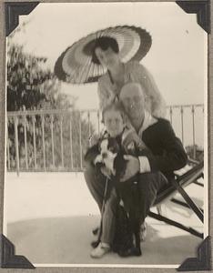 An unidentified man, woman and child, the child holding a Boston terrier