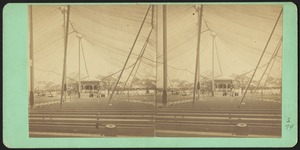 Interior view of a large tent with rows of benches and a bandstand