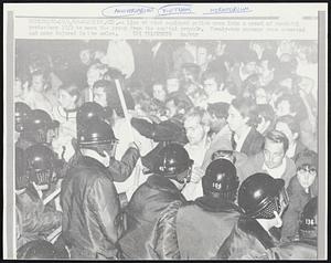 A line of riot equipped police move into a crowd of youthful protesters 10/3 to move the group from the capitol grounds. Twenty-two persons were arrested and many injured in the melee.