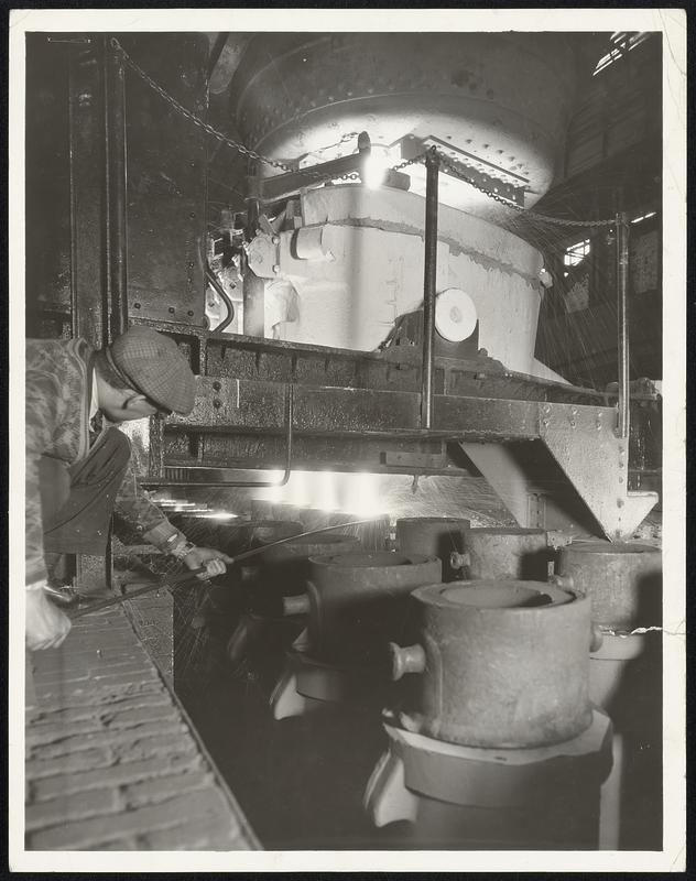 Ford Steel in the Making Here, in the great open hearth steel plant at the Rouge Plant of the Ford Motor Company in Dearborn, Michigan, molten metal is being poured from a giant ladle into ingot molds--one of the intermediate steps in the making of steel for the now 1935 Ford V-8 cars and trucks. Four molds are filled at one operation.