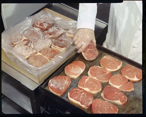 Frozen steaks being removed from box + placed on grill