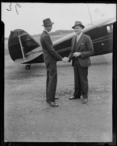 John Roosevelt with an unidentified man standing beside an airplane