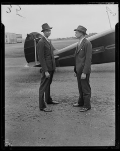 John Roosevelt with an unidentified man standing beside an airplane