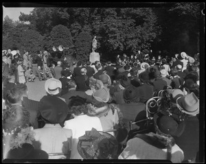 A crowd seated outdoors watching a speaker
