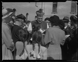 Rev. Cushing with a crowd of adults and children, signing a book