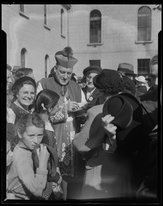 Rev. Cushing with a crowd of adults and children, signing a book