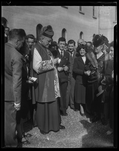 Rev. Cushing stands before a crowd signing a book