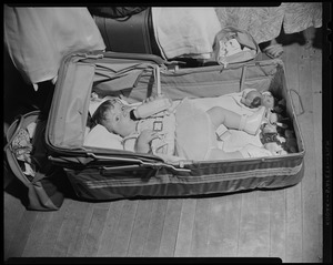 Child laying in makeshift bed with bottle