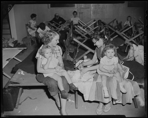 Women with children seated on a cot at a shelter