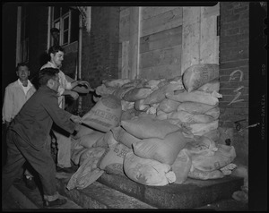 Men piling sandbags on a building entryway to prevent flooding