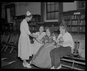 Red Cross volunteer with three women who sit in front of non-fiction bookshelves