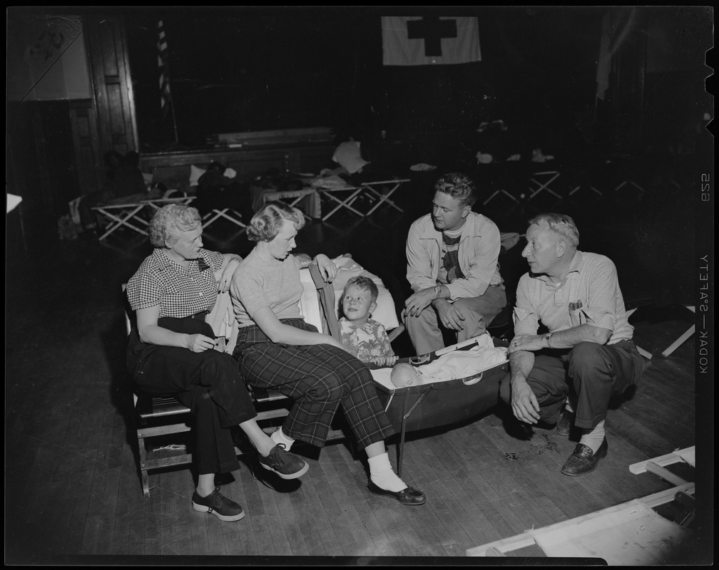 Group sitting with a baby in a portable bassinet