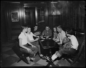 Group sitting around at table at a shelter, playing cards. One woman holds a dog
