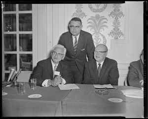 Three men at table, two are seated. Dr. Albert B. Sabin is seated on the far left