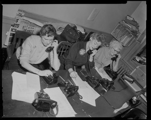 Three women seated at a table and answering telephones