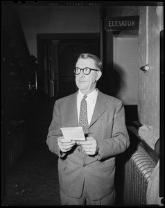 Man near an elevator sign, outside the courtroom