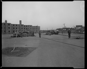 Military men in front of apartment buildings and cars