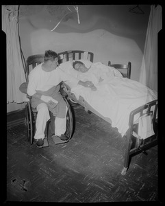 Man and woman holding hands in bed and wheelchair