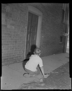 Boy who witnessed suspect entering building, sits on the ground and looks towards doorway