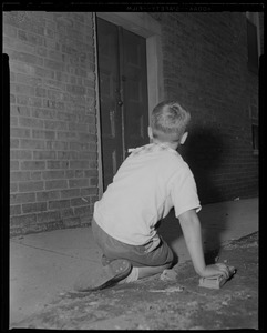Boy who witnessed suspect entering building, sits on the ground and looks towards doorway