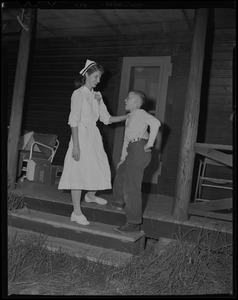 Nurse talking with a young boy on a front porch