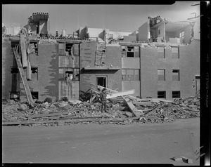 Military man standing in front of damaged building