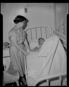 Woman standing at a boy's bedside