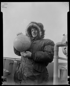 Navy officer wearing a fur-lined hood and holding globe