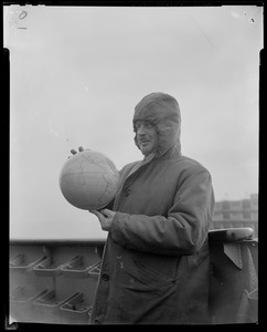 Navy officer wearing a hood and holding globe