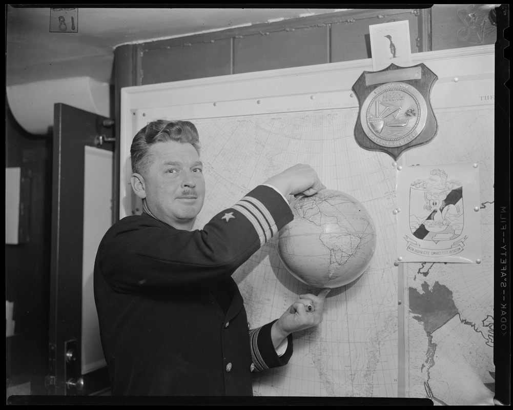 Navy officer holding the globe with his two pointer fingers