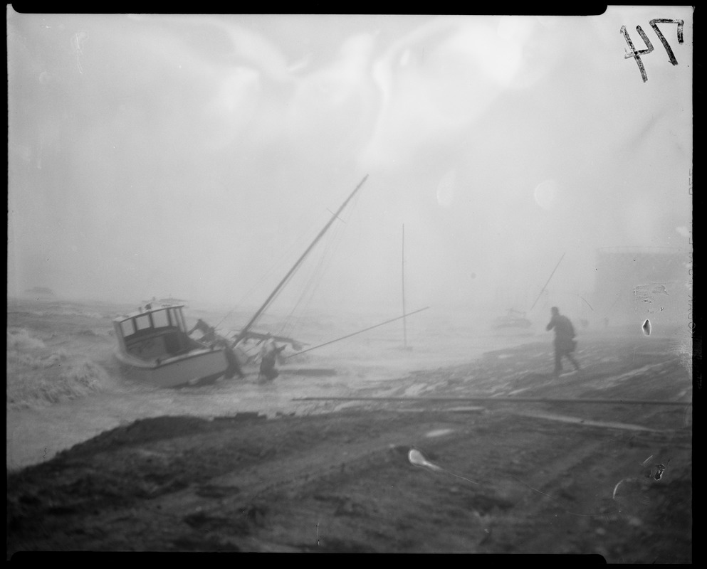 Men helping secure boats along stormy coastline