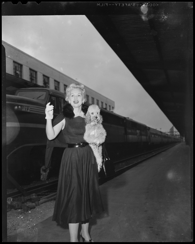 Eva Gabor, standing and holding her dog Delilah