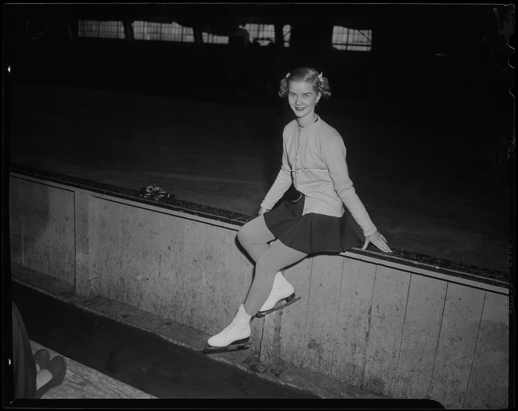 Barbara Ann Scott sitting on the rink boards, with skates on