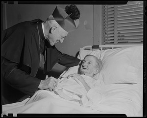 Archbishop Richard J. Cushing visiting patient laying in bed